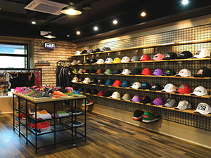 An image of a hat store with rows of baseball caps displayed on wire grid