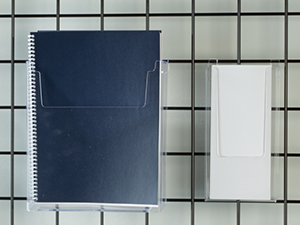 A close up shot of a notebook in a clear holder attached to black wire grid